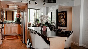 Una cocina moderna con una isla central, armarios de madera y una zona de comedor con sillas.