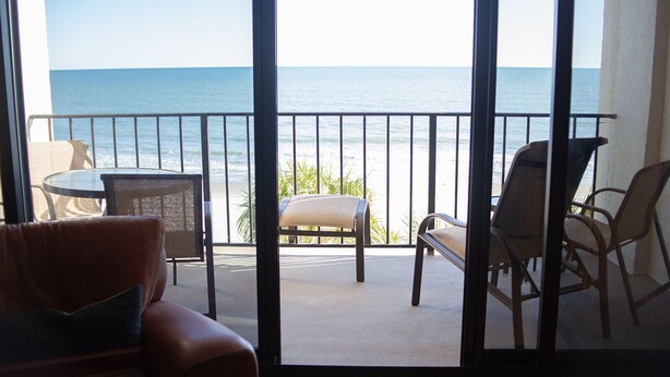 Un balcón con vistas al mar, amueblado con un sofá, sillas y una mesa.