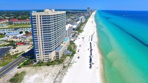 Een hoog hotel naast een strand met helder turquoise water.