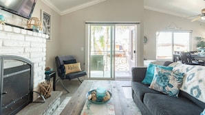Un salon avec une cheminée, un canapé, une table basse et une vue sur l’extérieur, accessible par une porte-fenêtre coulissante.