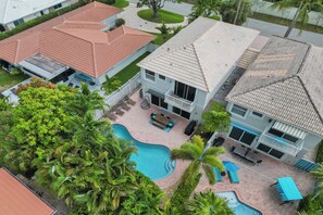 Une maison à deux étages avec une piscine, un patio doté de mobilier d’extérieur et un jardin bien entretenu.