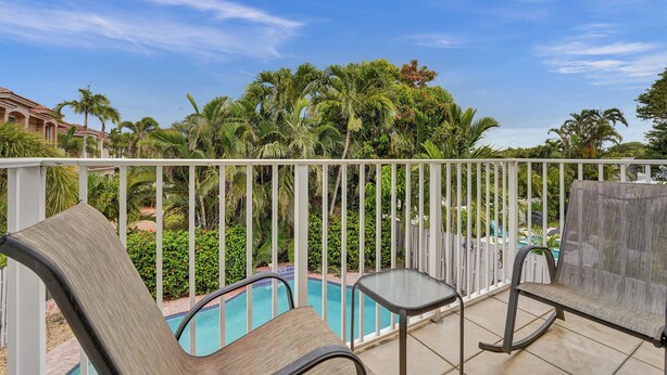 Un balcon avec une piscine, du mobilier d’extérieur et une végétation luxuriante.