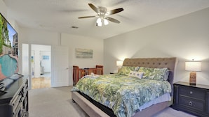 Une chambre à coucher avec un lit, des tables de chevet, un ventilateur de plafond et un tableau accroché au mur.