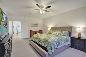 Une chambre à coucher avec un lit, des tables de chevet, un ventilateur de plafond et un tableau accroché au mur.