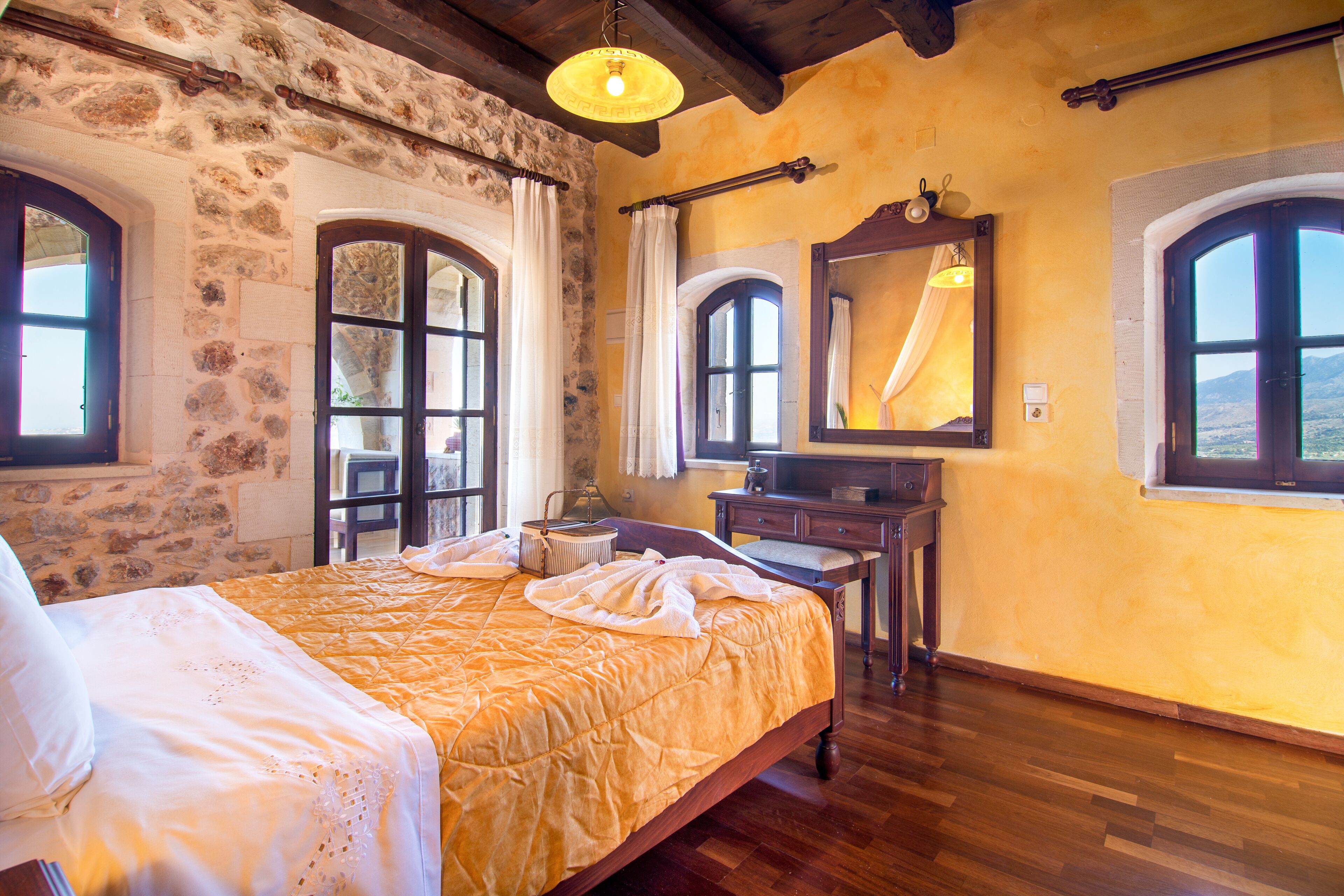 A room with a bed, a dresser, and two windows with curtains.