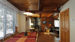 A wooden dining area with a table and chairs, a fireplace, and a cozy living space with a couch and a coffee table.
