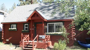 A log cabin with a front porch, a small staircase, and a blue canoe in the background.
