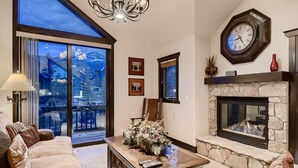 Un salón amplio con un gran ventanal, chimenea y una araña.