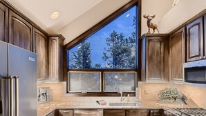 Una cocina moderna con un ventanal grande, electrodomésticos de acero inoxidable y armarios de madera.