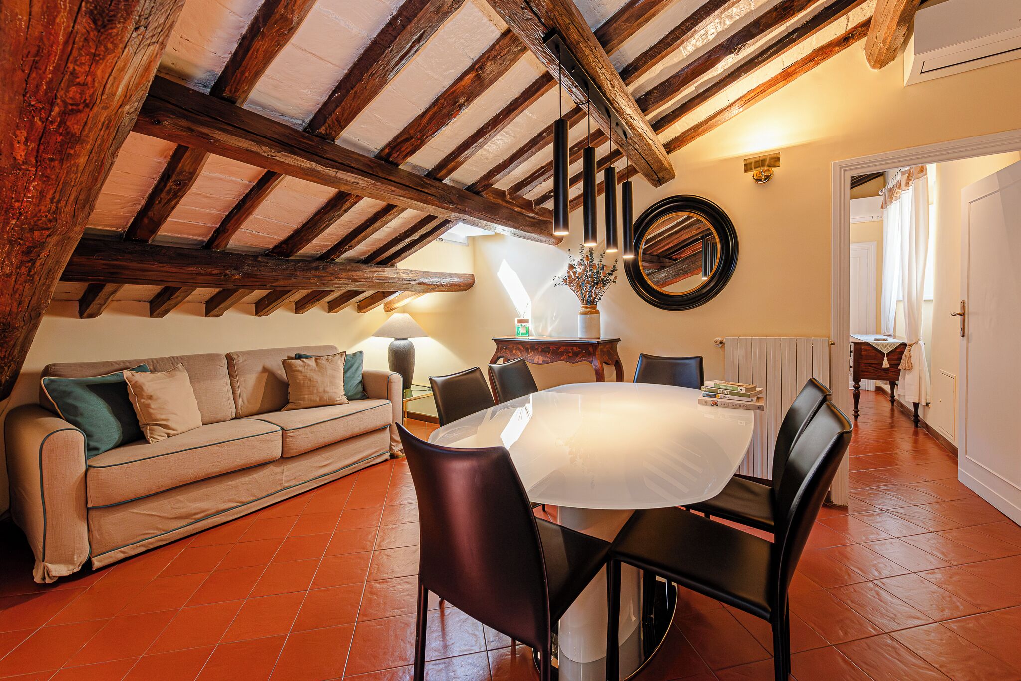 Una sala de estar acogedora con techo de madera, una mesa redonda y un sofá.