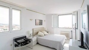 Une chambre à coucher moderne avec un lit, des tables de chevet, un bureau et un téléviseur.