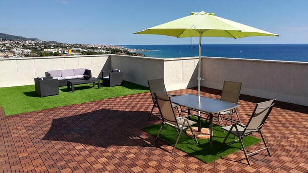 Une terrasse sur le toit avec une table et des chaises, une pelouse verdoyante et une vue sur la mer.