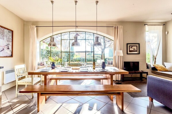 A dining area with a wooden table, benches, and pendant lights.