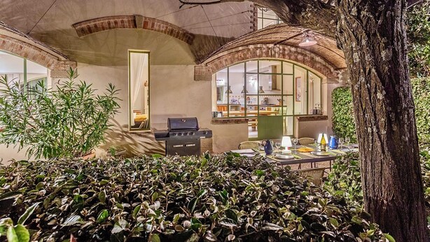 An outdoor dining area with a grill, tables, and chairs, surrounded by lush greenery and a large tree. - Unique house with air con, wine country, pool 18x5, close Avignon (Cairanne)