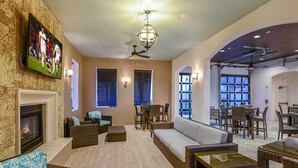 A spacious indoor area with a fireplace, comfortable seating, and a television displaying a sports event.