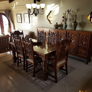 Uma área de refeições com mesa e cadeiras de madeira, parede de tijolos e um candelabro.