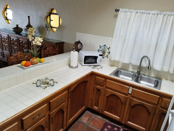 A kitchen with wooden cabinets, a white countertop, a sink, a microwave, and decorative tiles. - (17#1 ) romantic and cozy condo in Las Gaviotas en Playas de Rosarito (Playas de Rosarito)