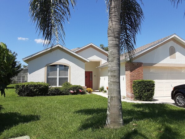 A residential house with a garage, a front lawn, and a palm tree.