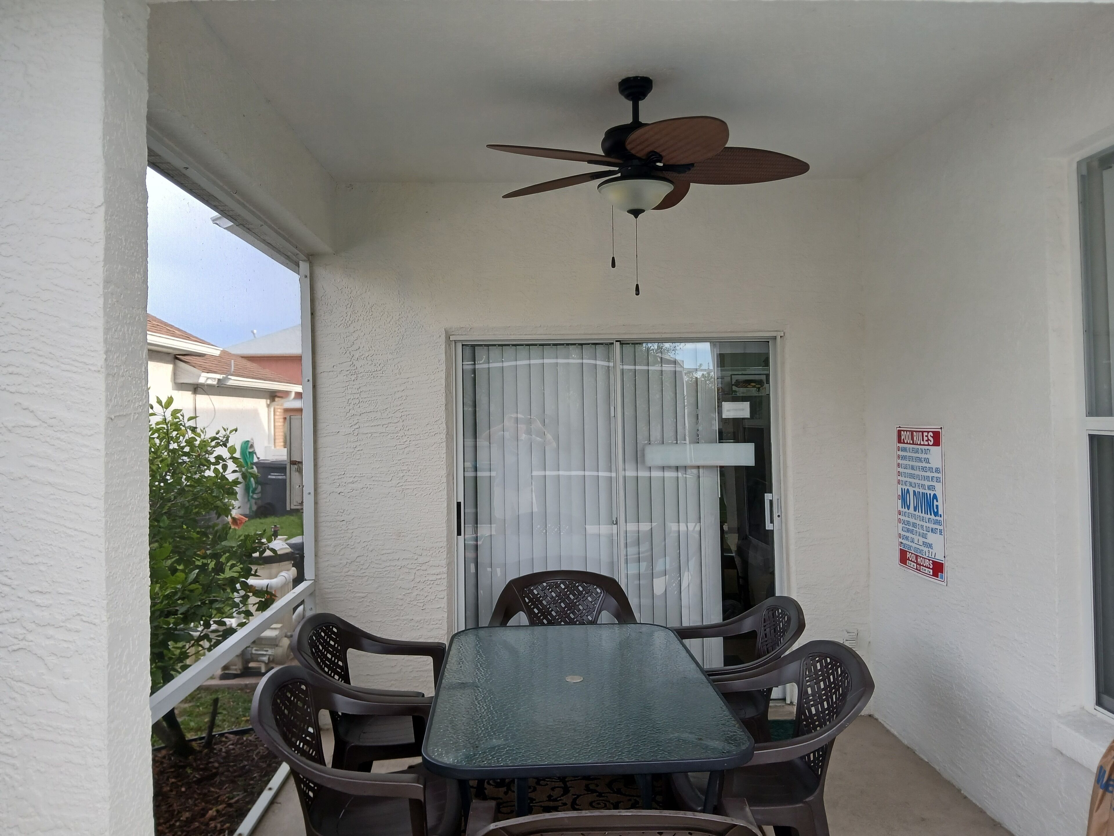 A balcony with a table and chairs, a ceiling fan, and a sliding glass door.