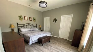 Een slaapkamer met een bed, nachtkastjes, een bankje en een houten dressoir.