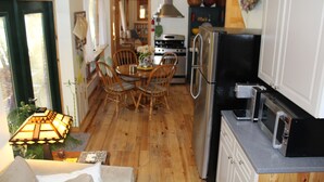 Cocina compacta con comedor, suelo de madera y ventilador de techo.