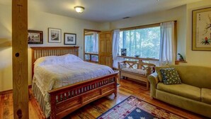 Un dormitorio con cama de madera, un sofá y una ventana con cortinas.