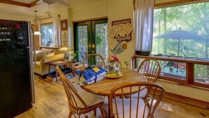 Un comedor acogedor con sillas de madera y una mesa, un refrigerador y una ventana con vista a árboles.