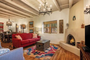 A cozy living room with a red sofa, a fireplace, and a television. - Incredible Location, Hot Tub, Roof Deck (Santa Fe)