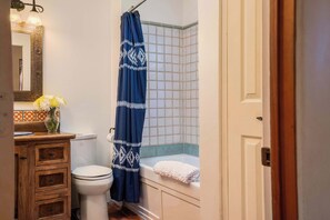 Une salle de bain comprenant des toilettes, un lavabo avec un miroir, un rideau de douche bleu et une baignoire avec une serviette.