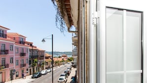 En balkon med udsigt over en gade fyldt med parkerede biler og bygninger.