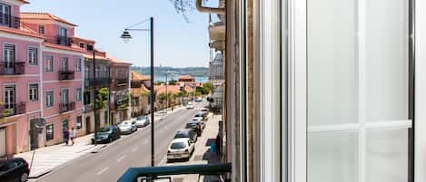 Un balcón con vistas a una calle bordeada de coches aparcados y edificios.