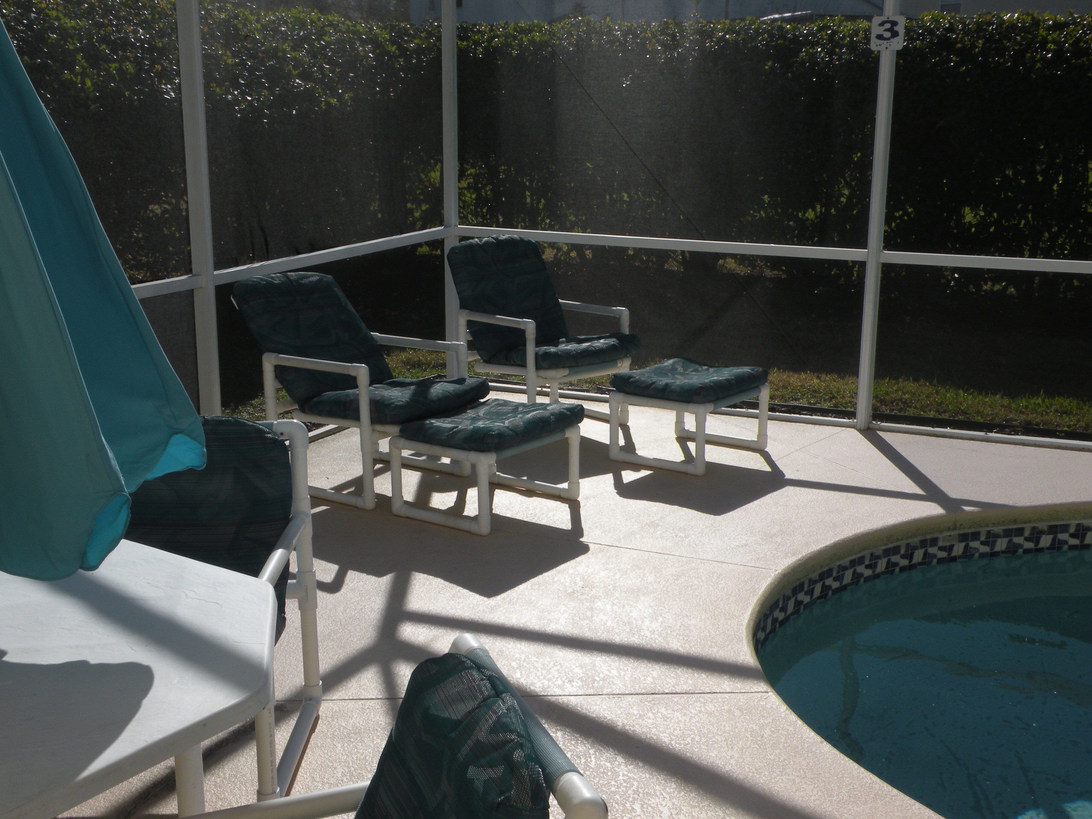 Un área junto a la piscina con sillones de descanso y una piscina.