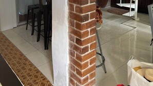 A spacious living area with a brick column, a hanging lamp, a spiral staircase, and a dining area with chairs and a table. -  Sunset Vista (Canefield)