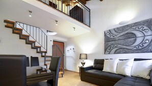 Una sala de estar moderna con una escalera, un sofá y una zona de comedor.