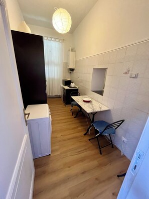 Eine kleine Küche mit Esstisch, Stühlen, einem Kühlschrank und einer Pendelleuchte.