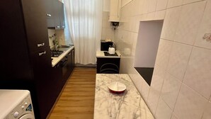 Et kompakt køkken med vaskemaskine, et lille spisebord og en stol.