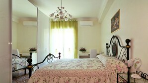 Una camera da letto con un letto, uno specchio, un lampadario e un quadro appeso al muro.