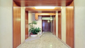 Un corridoio con pavimento piastrellato, rivestito in legno e decorato con piante in vaso.