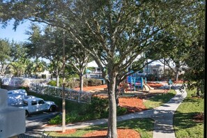Stroll through a serene neighborhood with a picturesque tree, playground, and lush surroundings.