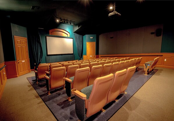 Ein Theater mit Sitzreihen, einer Leinwand und einer Bühne.