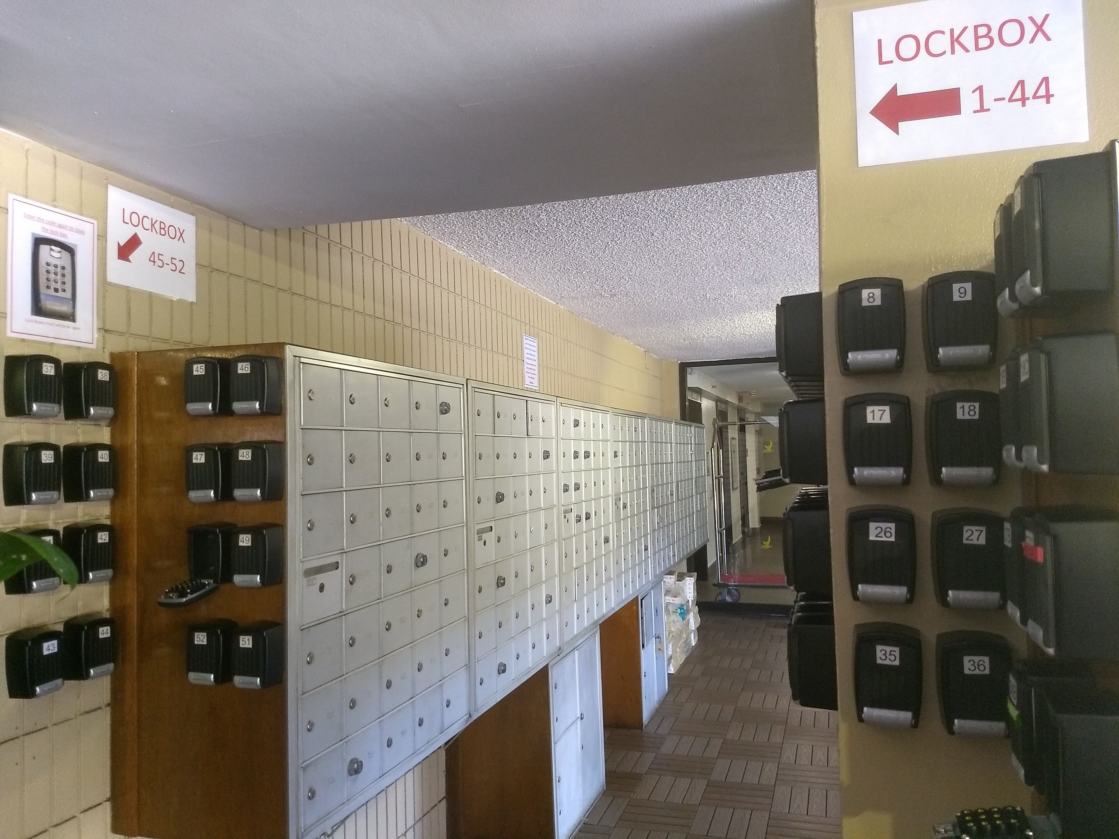 Eine Reihe von Schließfächern mit den Nummern 1 bis 44, ein Schild, das einen Schlüsselboxbereich kennzeichnet, und ein an der Wand befestigtes Telefon.