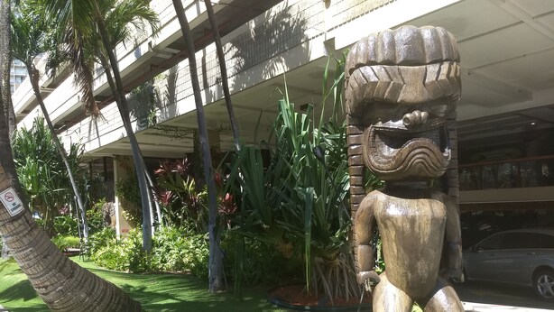 A tiki statue in a garden with palm trees and tropical plants, under a covered walkway. - Charming Studio in Waikiki - 2 Full size Beds, Free Wi-Fi (Honolulu)