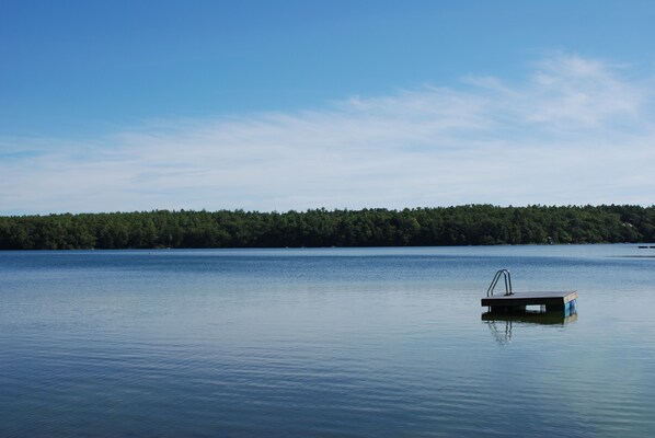 A calm lake with a dock extending into the water. - Cottage with Sandy Beach at Cornish Point on Long Pond (Plymouth)