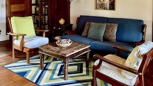 A cozy living room with a blue sofa, wooden chairs, a coffee table, and a ceiling fan. - Cottage on Beautiful Long Pond  with Fantastic Sandy Lakefront Beach (Plymouth)