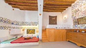 Una habitación con un banco de madera, un tapete rojo, un muro decorado con platos y un armario de madera.