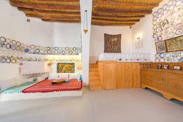 A room with a wooden bench, a red mat, a wall decorated with plates, and a wooden cabinet.