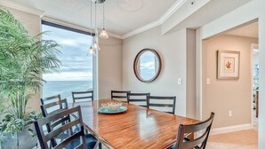 A dining area with a wooden table, chairs, and a view of the ocean.