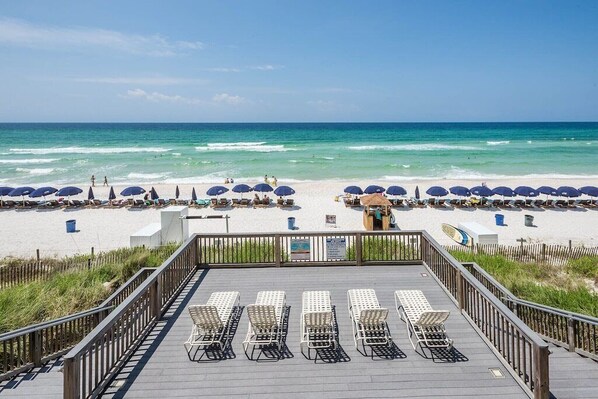 A beachside deck with sun loungers and umbrellas, overlooking the ocean.