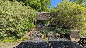 A garden with a pergola, outdoor seating, and lush greenery. - Large Mountain Lodge, Pet Friendly, w/ Hot Tub, and Sports Bar/Game Room. (Ripton)