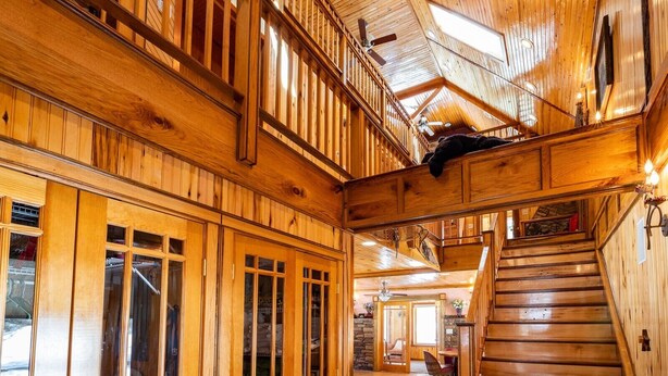 A wooden interior with a staircase, wooden railings, and a ceiling fan. - Large Mountain Lodge, Pet Friendly, w/ Hot Tub, and Sports Bar/Game Room. (Ripton)